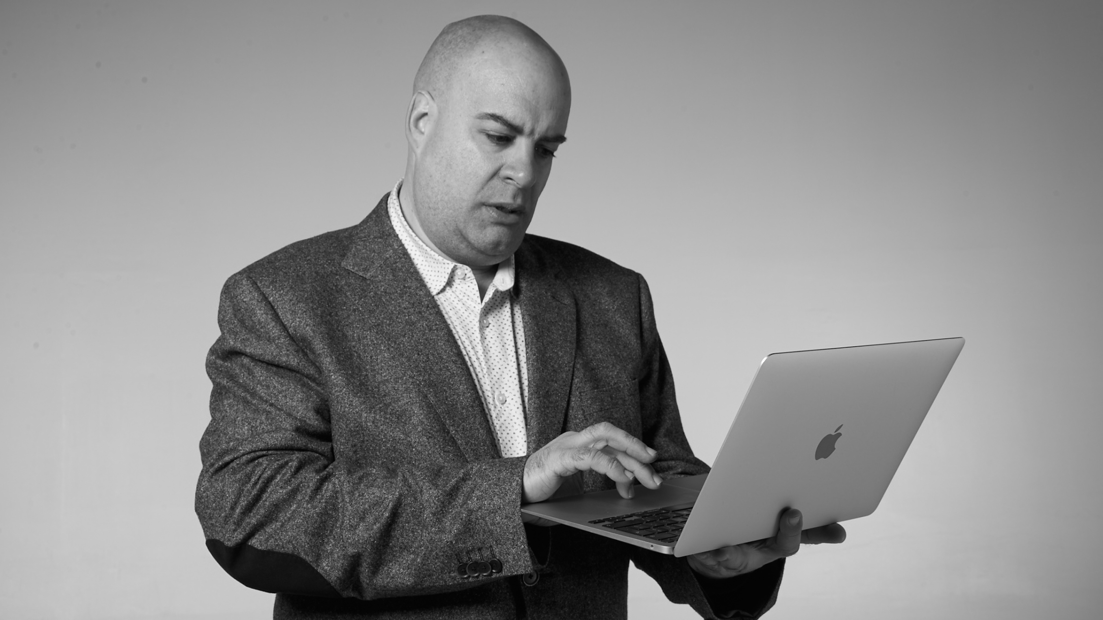 Man in a suit looking intently at an open Apple laptop.