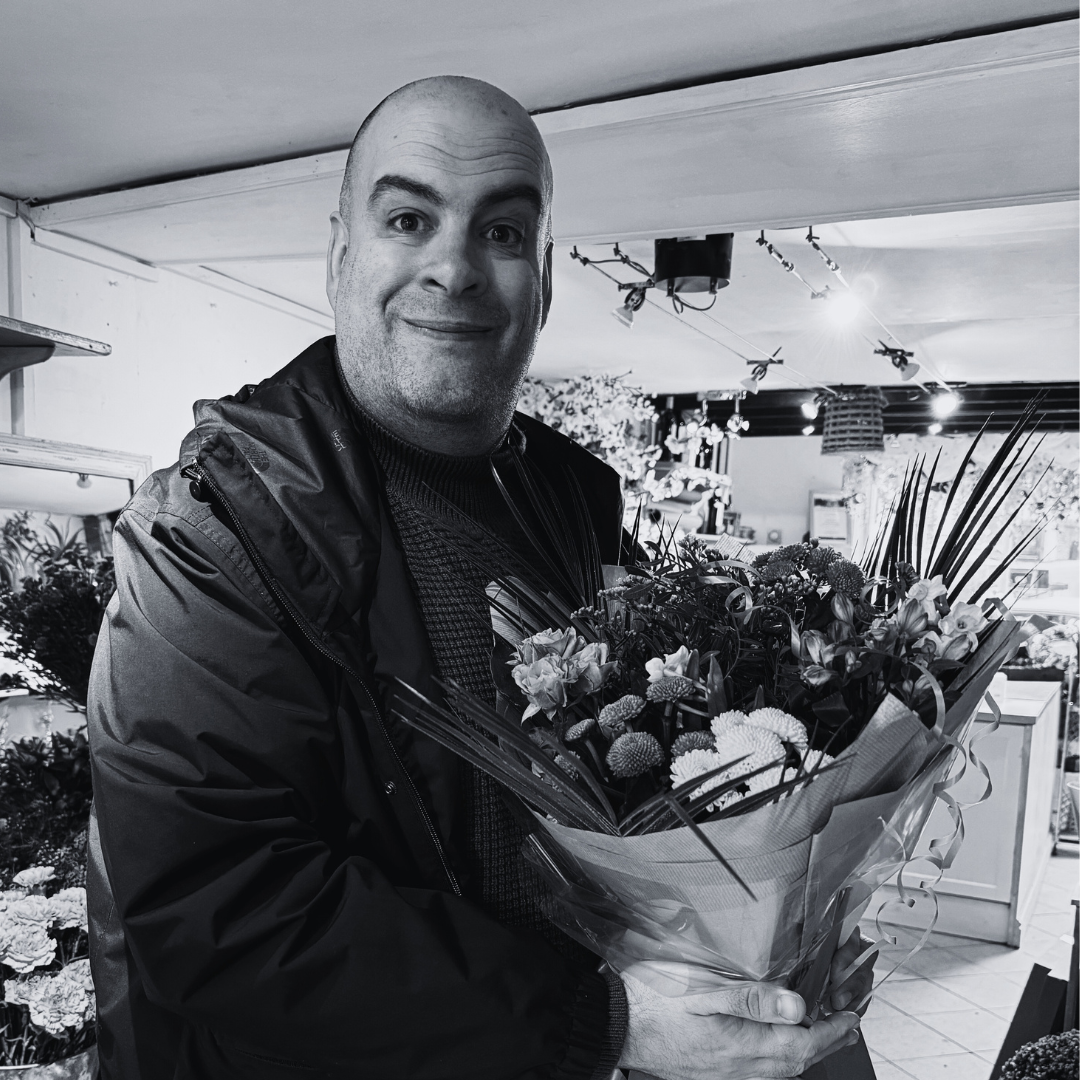 Smiling man holds a large bunch of flowers